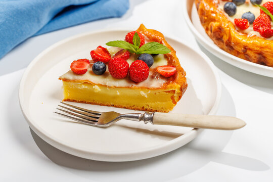 Slice of berry tart served on plate beside whole pie