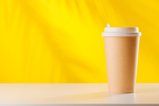 Disposable coffee cup on bright yellow background