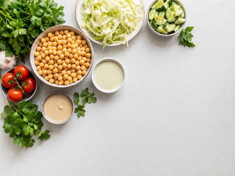 Preparaci&oacute;n de una ensalada fresca con garbanzos, verduras y salsas en una mesa