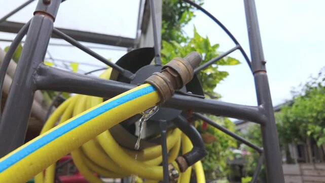 Low angle view of leaking irrigation hose connector with flowing water