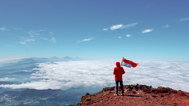 Solo hiker standing with the Indonesia red and white flag on the summit of Mount Slamet, Central Java