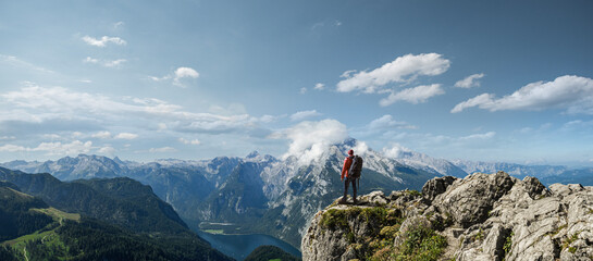 Wanderer auf einem Fels blickt auf Berge © m.mphoto