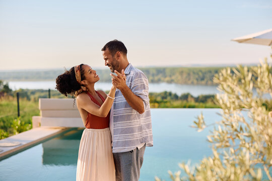 Romantic couple dancing by infinity pool in summer day.