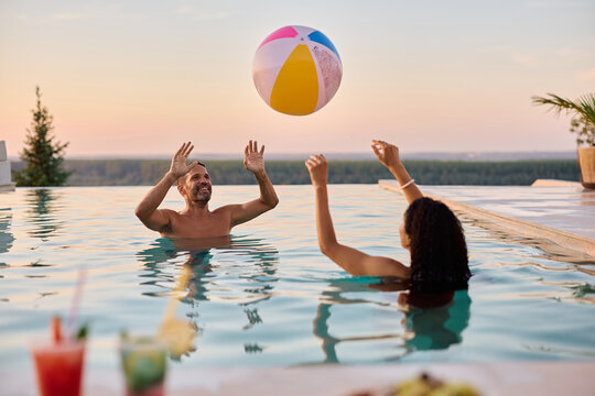 Playful couple having fun while playing volleyball in the pool.