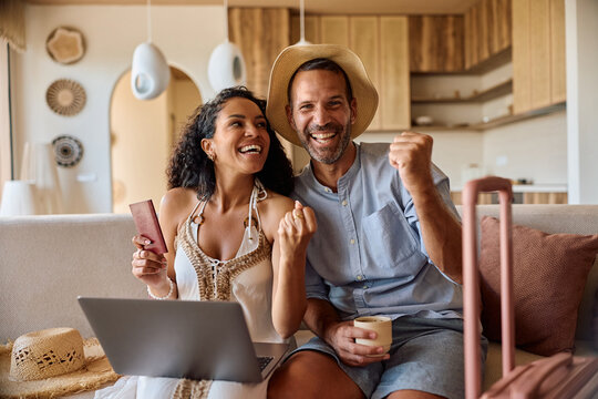 Happy celebrating their upcoming summer vacation while making online reservation over a laptop.