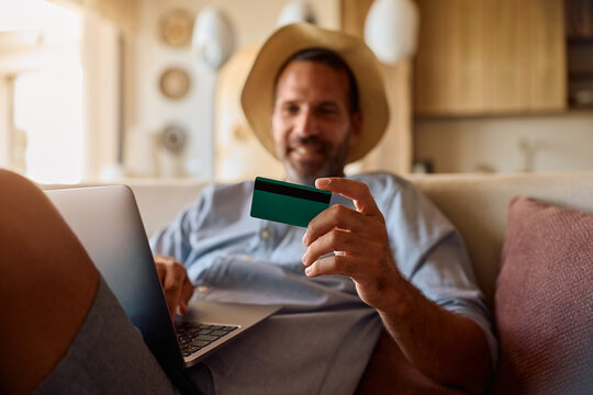 Close up of man using credit card while making online reservation over a laptop.