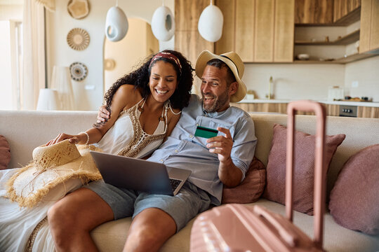 Cheerful couple making last minute travel arrangements online.