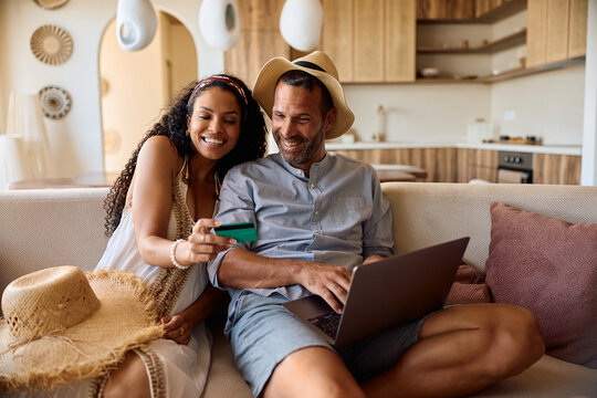 Happy couple booking their summer vacation online with credit card and laptop.