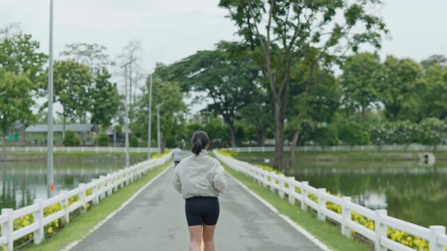 Woman running along a road beside a scenic reservoir, showing fitness, endurance, healthy lifestyle, outdoor exercise and longevity concept.
