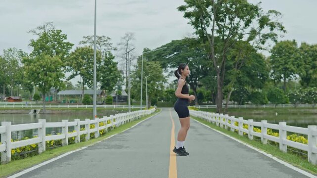 Woman warming up with light jogging by a reservoir road, showing outdoor fitness, healthy lifestyle, movement preparation and longevity concept.