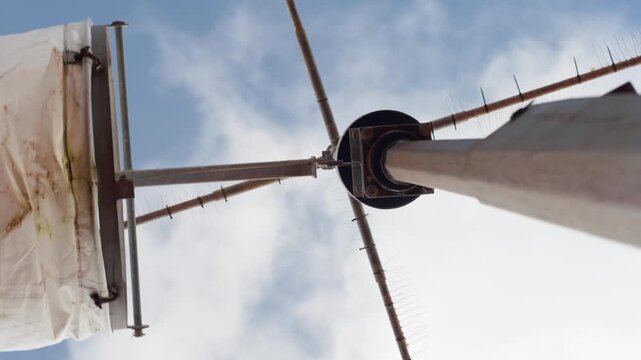 Vertical view of a windsock at a remote aerodrome gently moving in a light breeze against blue sky and passing clouds. Aviation, weather conditions and rural airstrip concept
