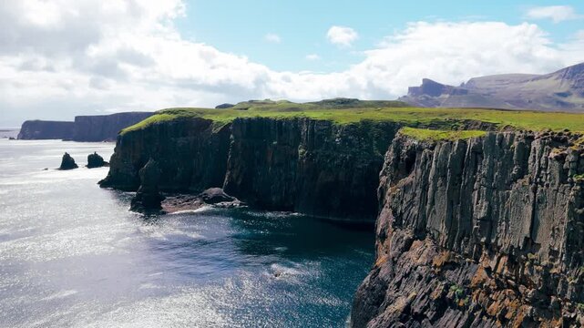 Drone footage reveals dramatic sea stacks and layered cliffs where the Atlantic meets the rugged coast of the Isle of Skye, Scotland.