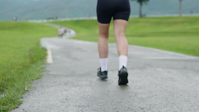 Woman starting a run on an outdoor path in a green park, representing healthy lifestyle, fitness, motivation and longevity.