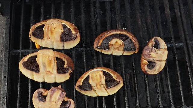 Slow Motion Close Up of Large Juicy Shiitake Mushrooms Grilling on Black BBQ Surface, Smoky Outdoor Cooking with Searing Heat and Gourmet Vegetables
