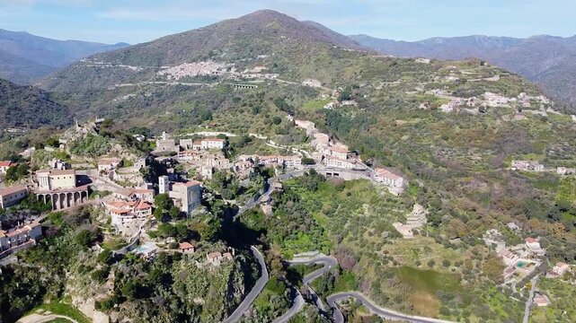 Sicilian hillside village Savoca surrounding lush green wild mediterranean valley and mountains on a sunny day, Province of Messina, Godfather wedding walk hiking area, Sicily, Revealing drone shot