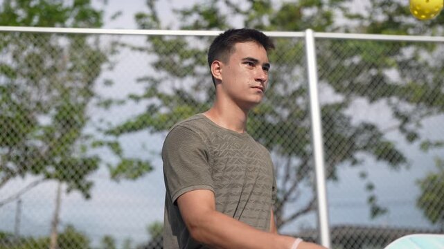 Athletic man in his workout clothes, practices pickleball on the sidelines to warm up before a match. Exercise for good health. Athlete practicing controlled trength, fitness, exercise, workout routin