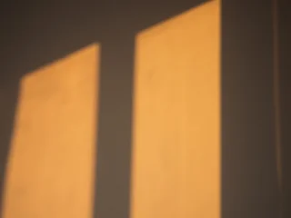 Warm golden sunset window light casting abstract geometric shadows on bright interior wall © blackday