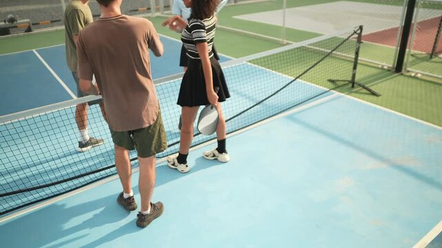 Enthusiastic pickleball players walk together and exchange respectful handshakes after outdoor training, strengthening friendships, teamwork, sportsmanship, physical fitness, active lifestyles.