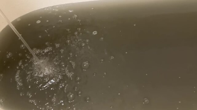 Bathtub filling with murky contaminated water,  unfit for drinking, water pipes