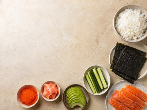 Preparaci&oacute;n de sushi con arroz, salm&oacute;n, aguacate, algas y otros ingredientes en una mesa