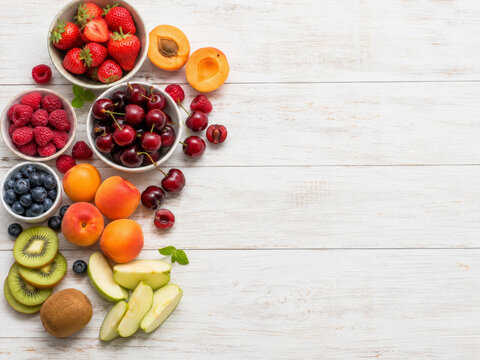 Variedad de frutas frescas dispuestas sobre una mesa de madera blanca, listas para comer o preparar recetas simples