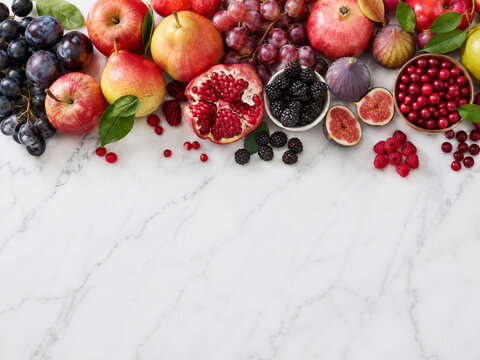 Varias frutas sobre una mesa de m&aacute;rmol en una cocina, incluyendo manzanas, uvas, higos y granadas