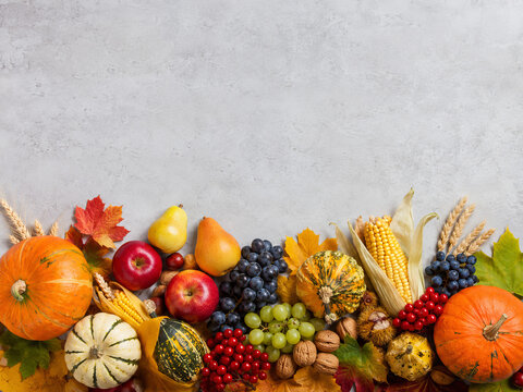 Varias frutas y nueces sobre una superficie gris en un arreglo colorido con hojas de oto&ntilde;o en una mesa