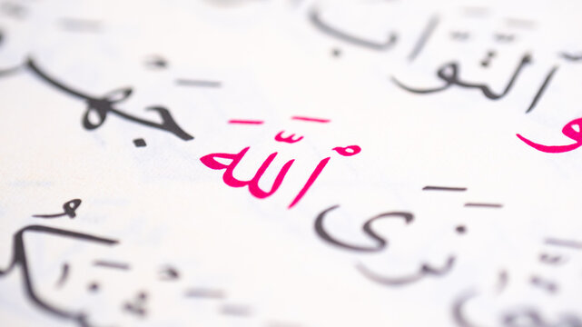 Macro close-up of the Arabic word &ldquo;Allah&rdquo; printed on a page with selective focus. Elegant Arabic calligraphy representing Islamic faith, religion, spirituality, and written Arabic typography.