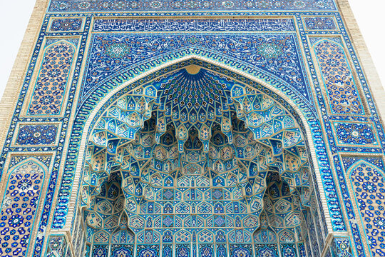 Ornate tiled portal of Gur-e-Amir mausoleum in Samarkand featuring muqarnas vaulting and geometric mosaic patterns. Ideal for travel publications, cultural heritage content, and architectural.