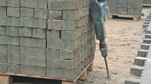 laying bricks at a construction site, balancing material on pallets. The area is busy with tools and organized segments of bricks displayed neatly for use