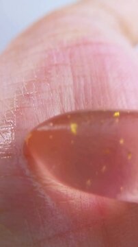Shiny reddish palm gently rubbed with pink lip balm. Close up view. Lip care product, moisturizing texture for beauty and self care concept.