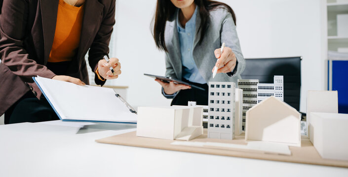 Real estate broker agent presenting and consult to customer to decision making sign insurance form agreement, home model, concerning mortgage loan offer in office