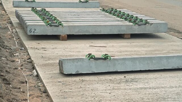 A construction team is setting up concrete panels on a worksite. The process involves aligning and positioning panels for a building foundation
