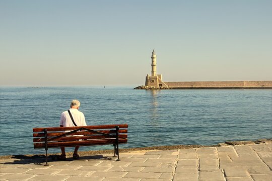 Chania waterfront and harbor with historic Venetian architecture and a lighthouse under a clear blue sky, Crete, Greece.