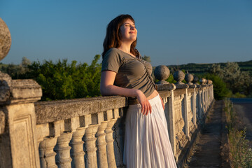 Fototapeta premium Young woman relaxing on stone balcony during sunset