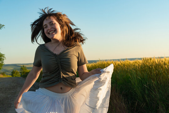 Happy young woman dancing in a wheat field at sunset