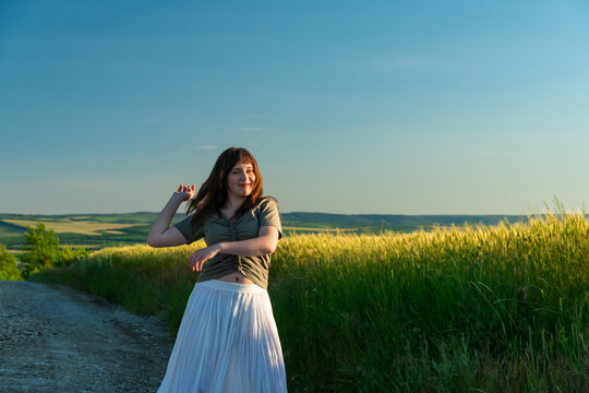 Young woman smiling and enjoying nature in a summer meadow at sunset