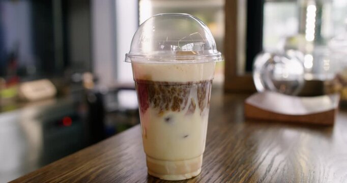 Preparing latte. Serving iced coffee. Barista hands covering plastic cup with dome lid on wooden counter making drink for takeaway.