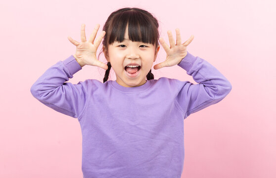 A funny little girl making a silly face and grimacing playfully towards the camera.