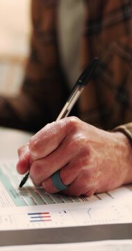 Person, hands and writing with documents for finance review, investment contract or application. Man, accounting and signing with paperwork, graph and chart for financial agreement and plan in home