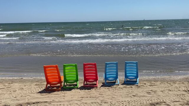 serie di sedie in plastica colorata in riva al mare