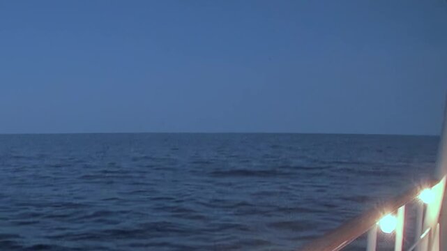 Witness majestic Arctic Ocean at dusk from cruising vessel. Gentle ripples softly break on calm water surface as distant horizon merges with muted sky. Peaceful northern passage unfolds.