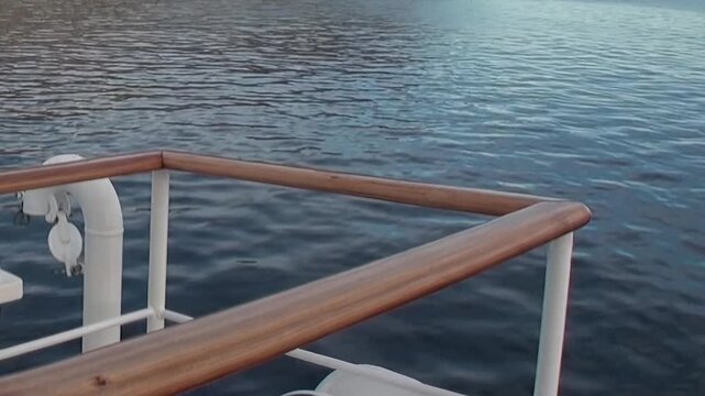 Gazing upon the vast, open waters of the Arctic Ocean from the deck of a vessel. The ship's sturdy railing frames the endless horizon where gentle ripples dance on the tranquil surface.