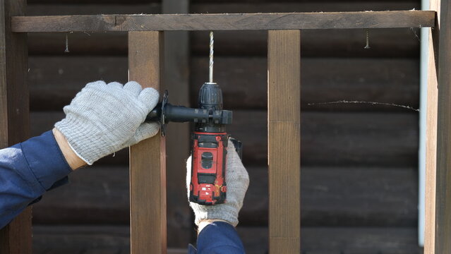 Builder worker using cordless hammer drill. Man with pneumatic perforator equipment making hole at construction. Installation process. Gloved hand grips the tool, precision and safety while working.