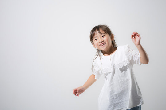 笑顔で楽しくダンス（踊る）する日本人の女の子　元気いっぱいに体を動かす健康な子ども　白背景コピースペースあり