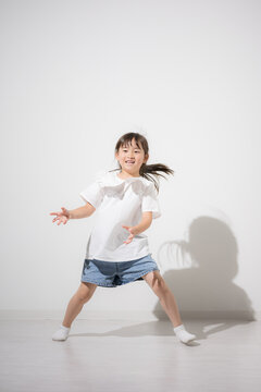 笑顔で楽しくダンス（踊る）する日本人の女の子　元気いっぱいに体を動かす健康な子ども　白背景コピースペースあり