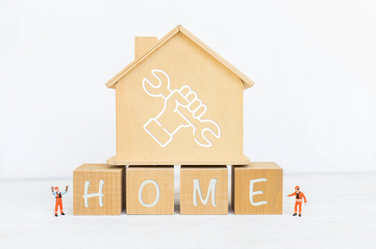 House model on wooden cube and miniature worker on white background, home maintenance service industry concept