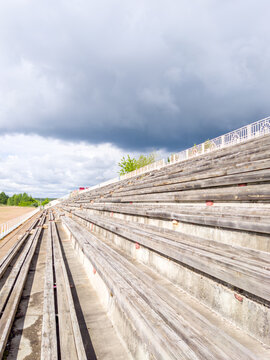 Empty wooden bleachers under cloudy sky outdoors