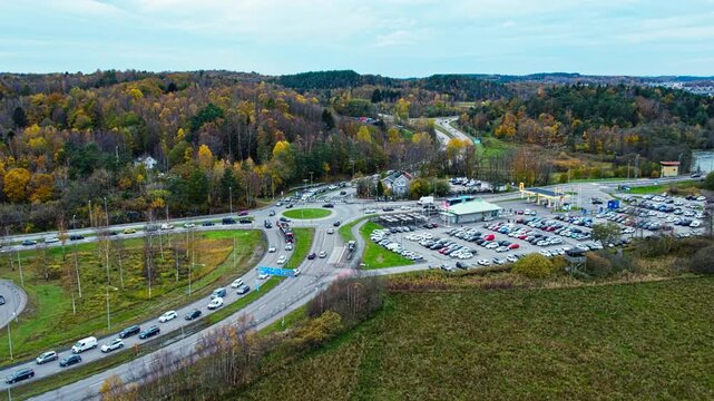 Aerial drone view of rush hour traffic near Jordfallsbron bridge in Kungalv Sweden. Busy roundabout roads parked cars and Vikingagrillen restaurant beside autumn woodland