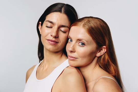 Two women embrace with head resting on shoulder